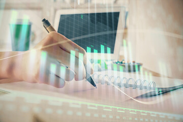 Financial forex graph drawn over hands taking notes background. Concept of research. Multi exposure