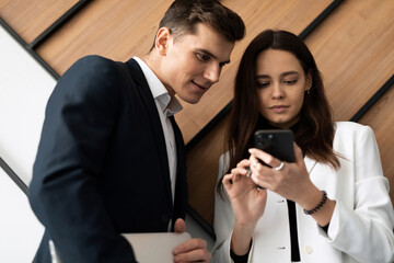 colleagues man and woman communicate during a break demonstrating a mobile phone