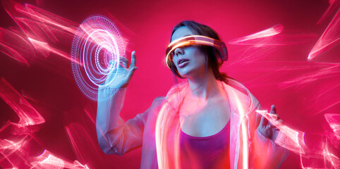 Obraz na płótnie Canvas Woman in futuristic costume. Girl in glasses of virtual reality while touching air. Augmented reality game, future technology, AI concept. VR. Neon red light. Viva magenta color of the year 2023. 