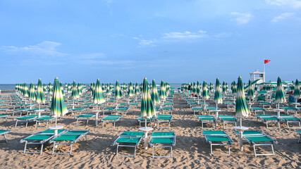 Deckchairs and parasols on sandy beach near the sea. Exotic beach in summer. Vacation, travel and tourism concept. 