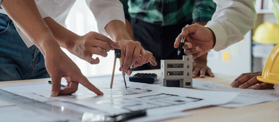 Cropped view of team engineers checking new construction project blueprints with engineering tools at work desk in office