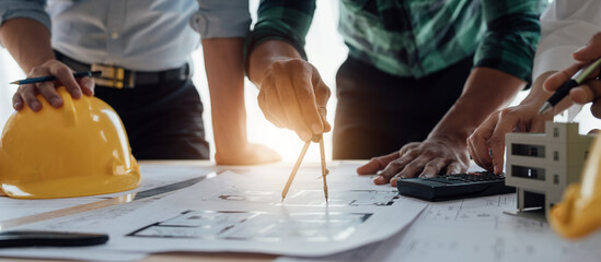Cropped view of team engineers checking new construction project blueprints with engineering tools at work desk in office