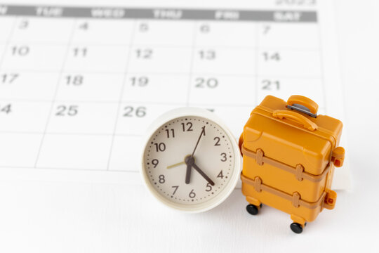 時計とカレンダーと玩具のキャリーバッグ。旅行の予定イメージ