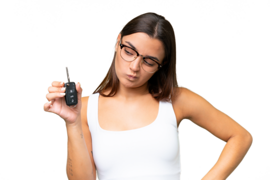 Young caucasian woman holding car keys isolated on green chroma background background with sad expression