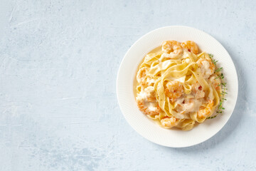 Seafood pasta. Pappardelle with shrimps and cream sauce in a white plate, with fresh thyme shot from above with copy space