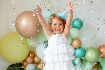 little girl celebrating birthday catches confetti