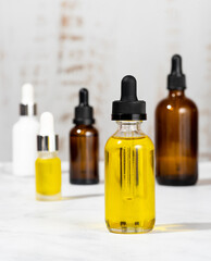 A set of organic cosmetics in glass vials with dropper for skin and hair care. Bottles with essential oils on the cosmetic table in the bathroom. The concept of self care and spa. Foreground focus