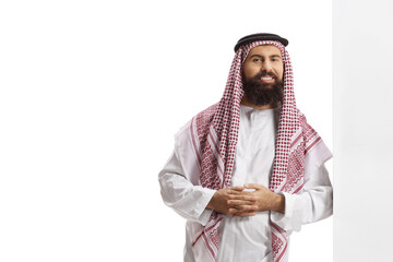 Saudi arab man wearing a traditional thobe and leaning on a wall