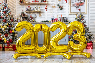 Close-up of golden balls in the form of numbers 2023 on the background of a Christmas tree standing in the studio. The concept of the new year and celebration.