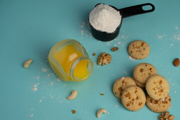 Freshly baked butterscotch cookies with its ingredients like dry fruits cow ghee and maida