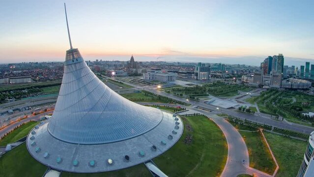 Aerial view over the city center with Khan Shatyr and central business district night to day transition timelapse before sunrise time from rooftop, Kazakhstan, Astana, Central Asia