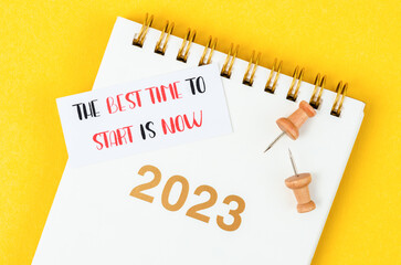The best time to start is now and desk calendar 2023 on yellow background.