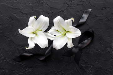 Fototapeta na wymiar Flowers heads of white lilies with black ribbon. Mourning or funeral background