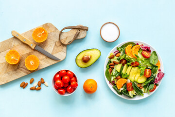 Overhead view of cooking healthy green salad with avocado and tomatoes