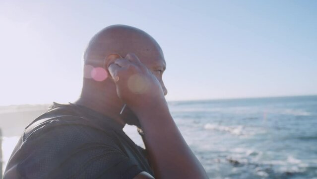 Beach, fitness and music of black man with peace, focus and calm energy for workout, training and mental health wellness. Ocean, summer lens flare and african sports or athlete listening to audio app