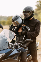 Man and woman in motorcycle helmets near the bike