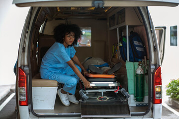 black nurse sits on an ambulance preparing to receive an accident or emergency patient to provide first aid and take the patient to the hospital.