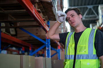 Handsome white worker finishes delivering goods in distribution center tired wiping sweat with...