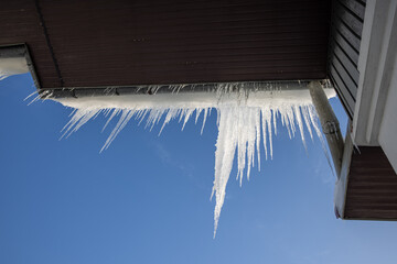 large icicles hanging from the roof on blue background