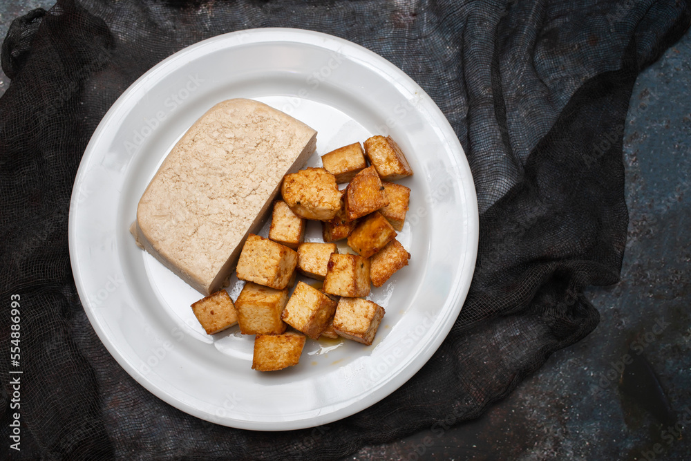 Poster raw tofu block on white small dish on dark