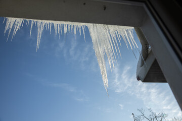 large icicles hanging from the roof on blue background