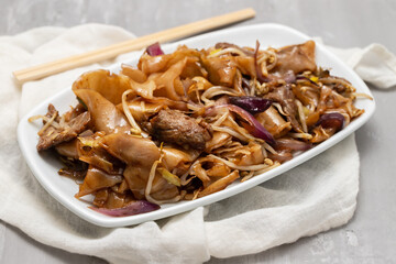 Fried noodles with vegetables and beef in white dish
