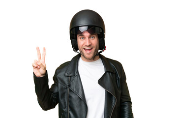 Young caucasian man with a motorcycle helmet isolated on green chroma background smiling and showing victory sign