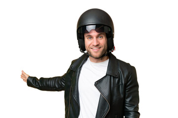 Young caucasian man with a motorcycle helmet isolated on green chroma background extending hands to the side for inviting to come
