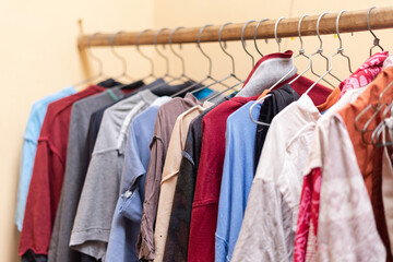 Defocus of drying colorful clothes with stainless hanger put on wooden pole indoor