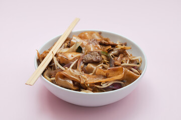 Fried noodles with vegetables and beef in white bowl