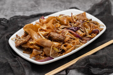 Fried noodles with vegetables and beef in white dish
