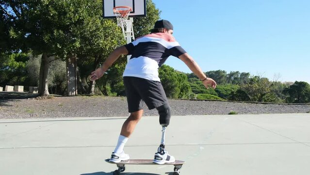 Sporty man with leg prosthesis stepping on skateboard and pushing off, riding it fast. Person with disability enjoying active leisure time in park. Amputee sport, active lifestyle concept 