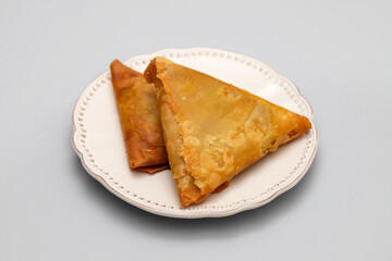 Two samosas with meat and vegetables on white plate