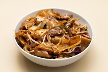 Fried noodles with vegetables and beef in white bowl
