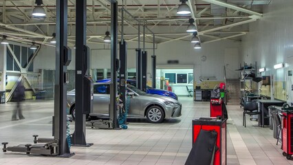 Cars moves on lifts in modern service station and men repair cars and make diagnostics timelapse. Car wash boxes on background