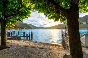 View from the lakefront Lungolago Europa promenade near a small pier looking across the lake at the...