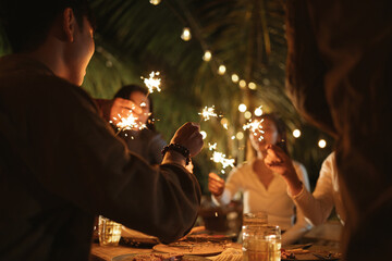 Selective focus hand. People holding firework sparklers having fun with friends group in new year...