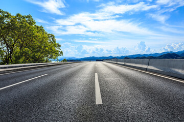 Asphalt road and green tree with mountain background