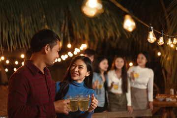 Happy Asian group friends in festival celebrating have fun with firework sparkler at night party outdoor. Group friends dinner party under light in the night. Festival celebrating.