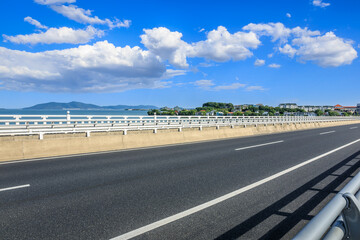 Fototapeta premium Asphalt road and river with mountain nature landscape under blue sky