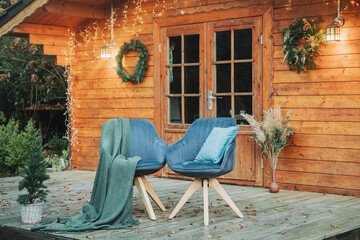 Two chairs outside on a wooden deck in winter. Seating outside in winter, at Christmas. Wooden house for winter holidays and Christmas holidays.