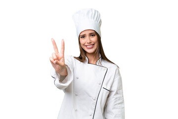 Young chef caucasian woman over isolated background smiling and showing victory sign