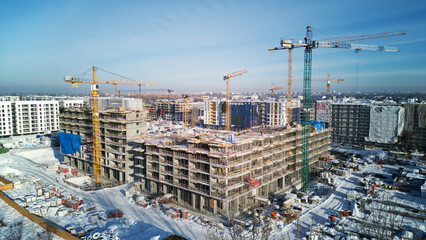 Crane and unfinished houses. Big construction site. Building construction in winter. Aerial view.