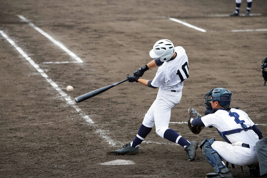 野球の試合でヒットを打つ高校球児