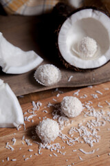 Close up of coconut with white pulp, coconut chip and white candies on wooden background..