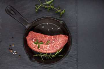Top Blade beef steaks in cast iron pan on black background.