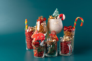Glass cups with Christmas decor against dark green background