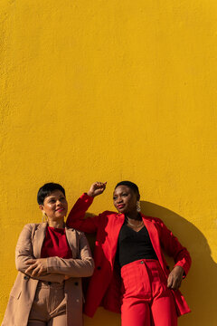 Confident diverse female models leaning on yellow wall