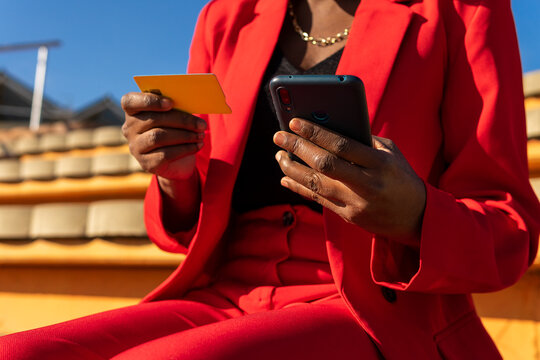 Cropped anonymous black woman making payment via smartphone with credit card