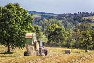 Heuernte,  Traktor mit Rundballenpresse - 554898376